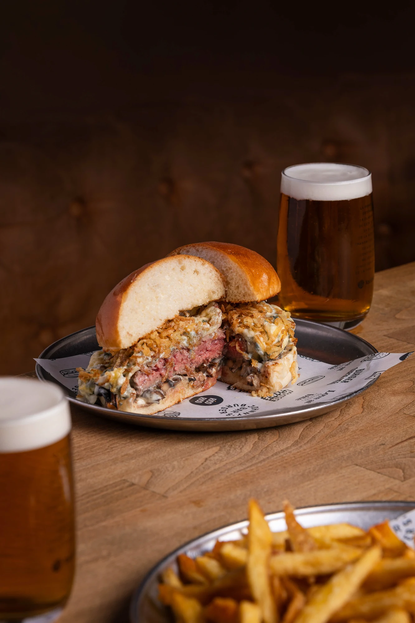 Burger cut in half with crispy onion, served with beer and fries