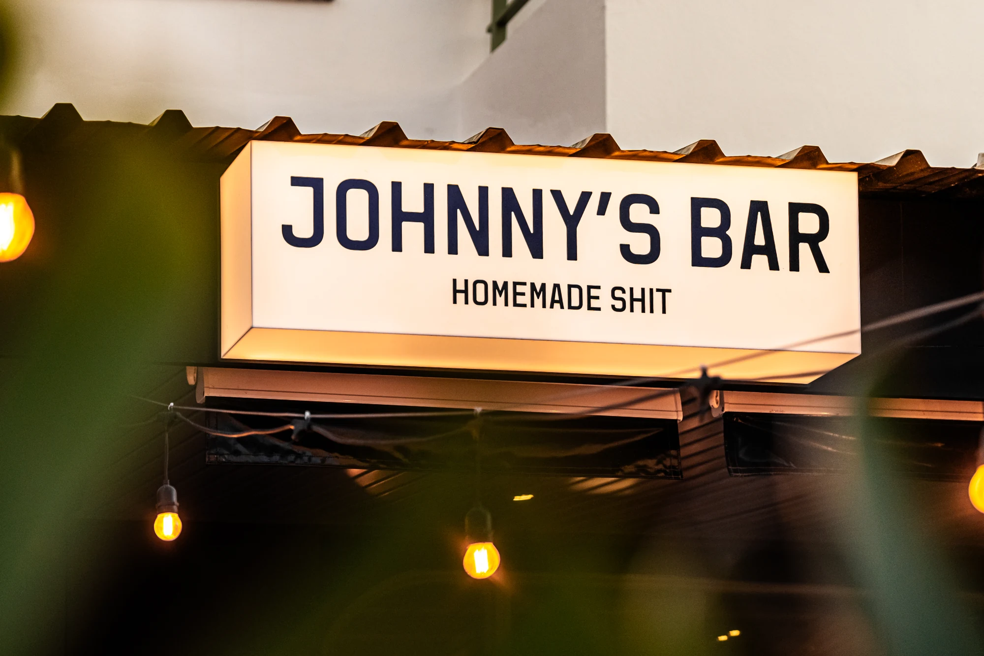 Johnny's Bar illuminated sign at dusk in Cala de Bou
