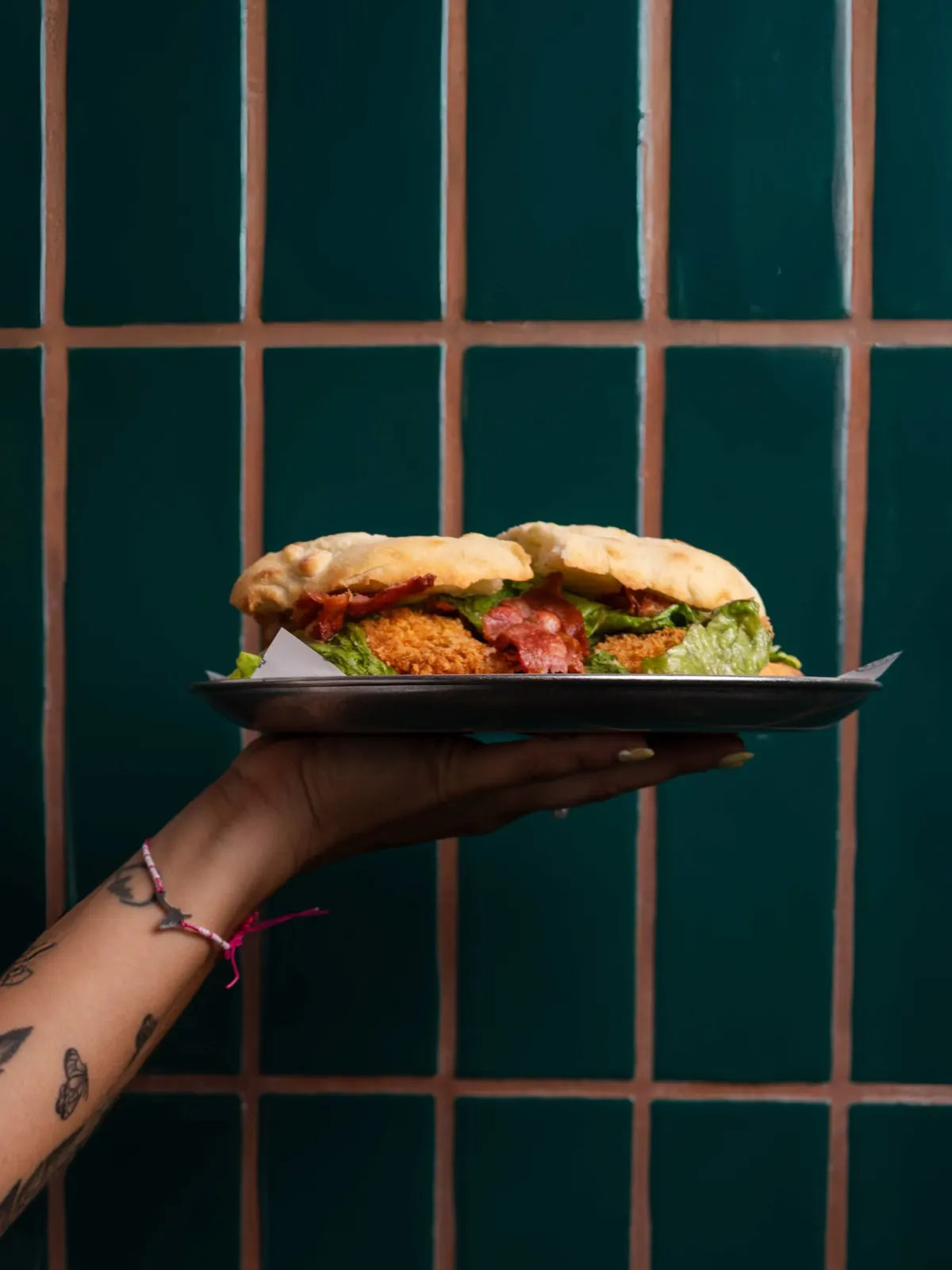 Crispy chicken sandwich with bacon held by hand
