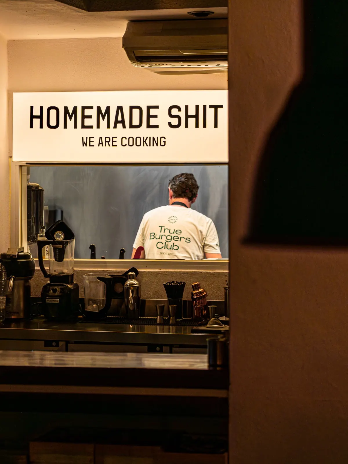 Johnny's kitchen seen through the Homemade Shit hatch with chef cooking